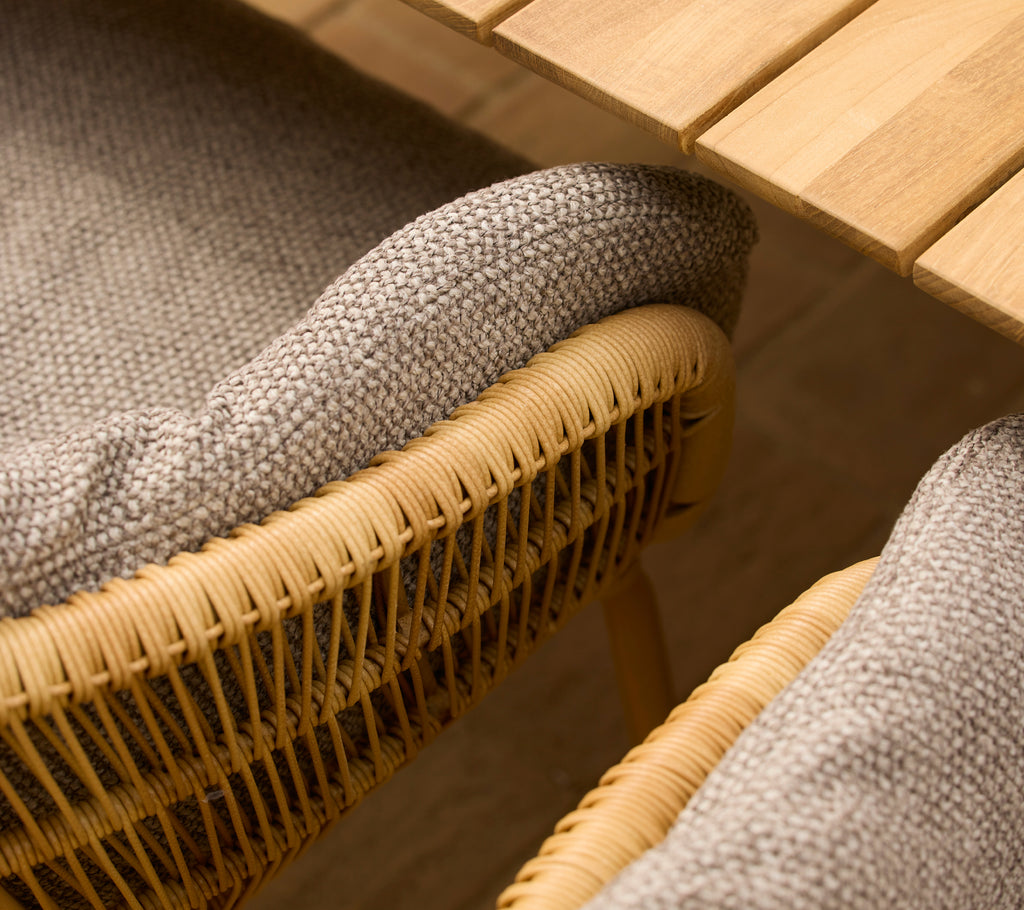 Helle braune Reis-Kissen auf einem Esszimmerstuhl mit eleganten Aluminiumbeinen, die gewebte Details und eine natürliche Ästhetik präsentieren.