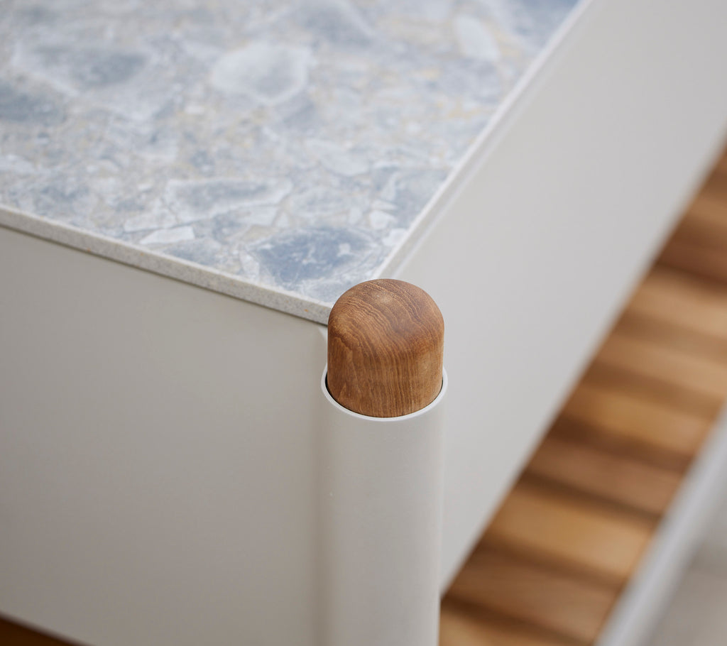 Holzeckdetail eines Möbelstücks mit einer strukturierten Oberfläche und vertikalen Stützen, die eine moderne Ästhetik betont.