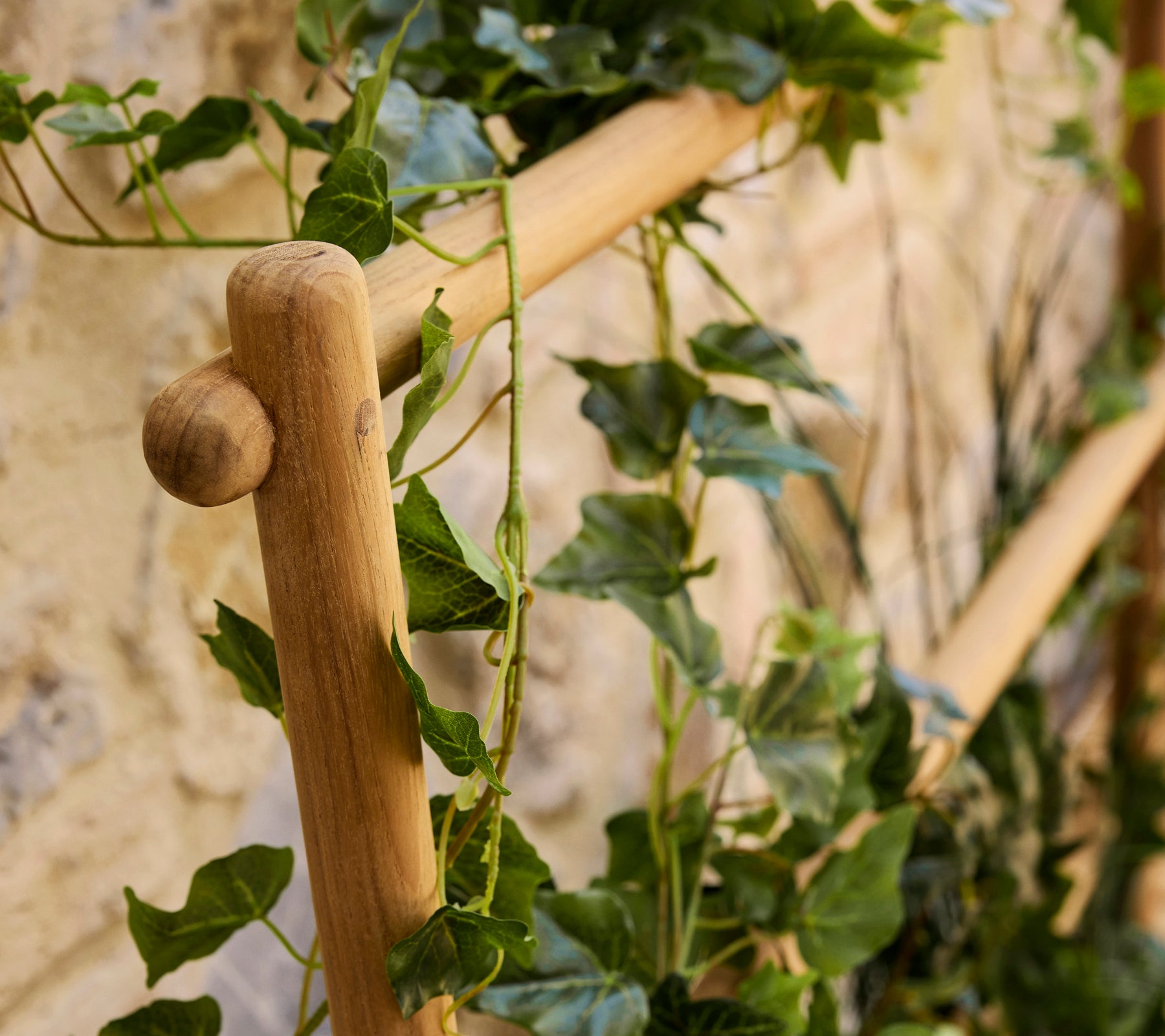 Ein Holzstabpflanzer mit üppigen grünen Ranken, die herabfallen und der Präsentation eine natürliche Note verleihen.