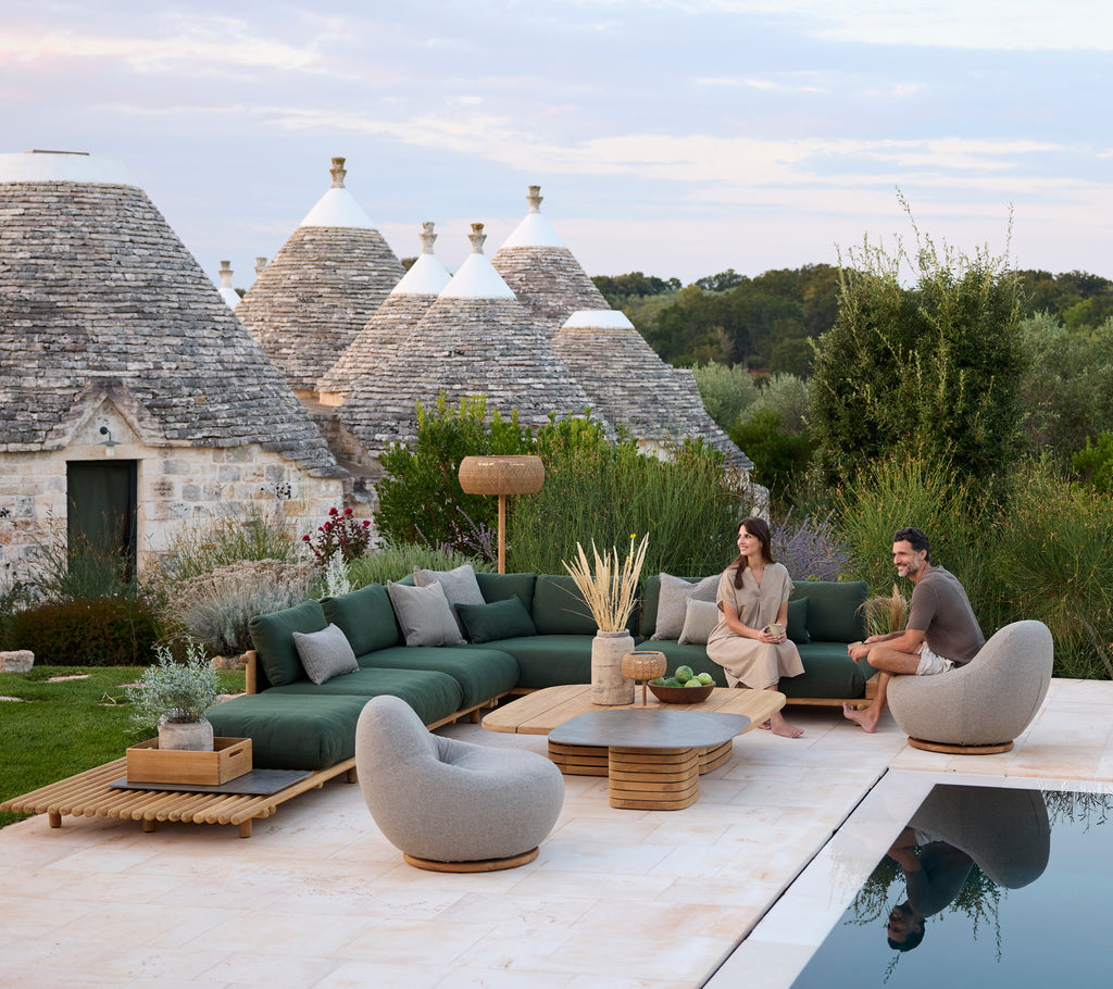 Moderne Außenlounge mit grüner Ecksofa und grauen Stühlen am Pool.