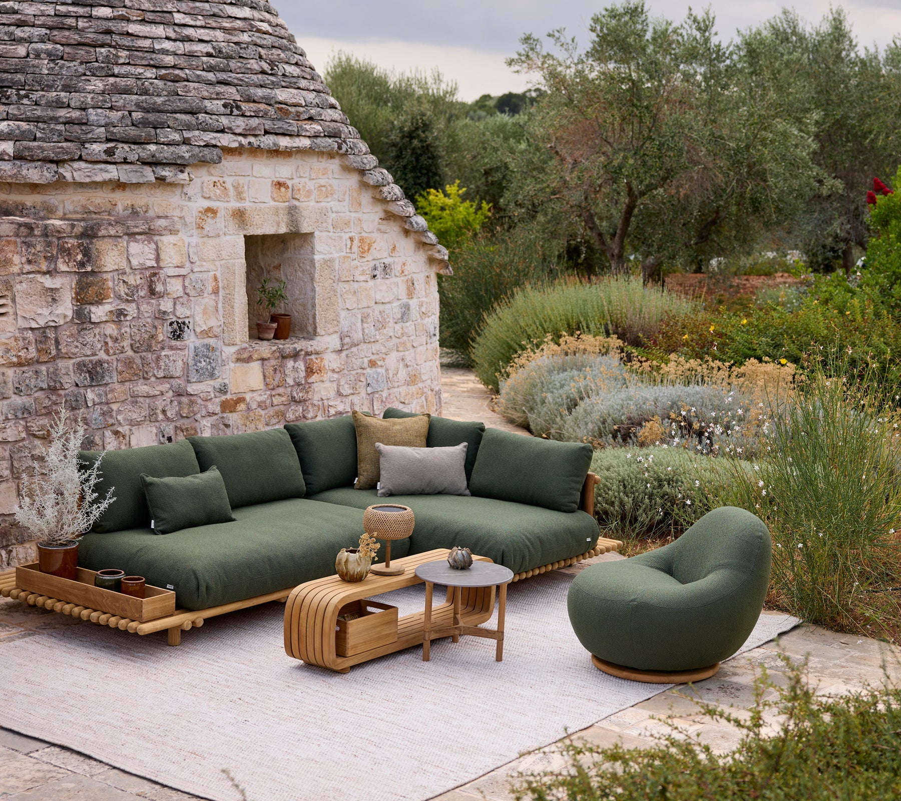 Moderne grüne Sofa mit runder Stuhl und Couchtisch in einer Außensitzgruppe.