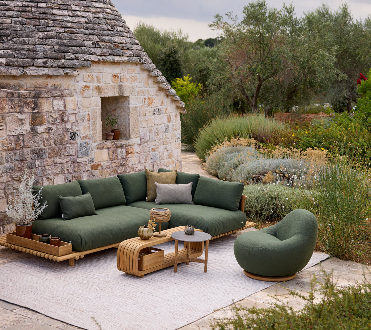 Moderne grüne Sofa mit runder Stuhl und Couchtisch in einer Außensitzgruppe.