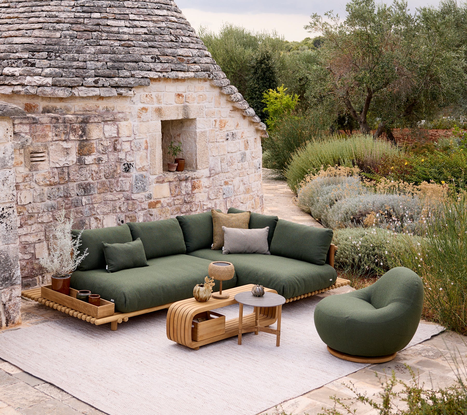 Modernes grünes Sofa und Stuhl mit einem braunen Tisch in einem Gartenambiente.