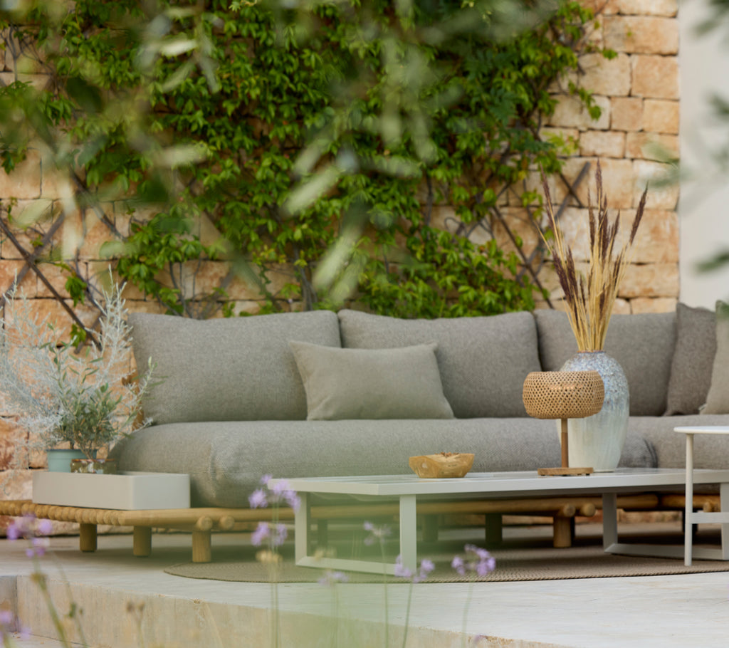 Moderne graues Sofa mit einem Holztisch in einem stilvollen Außenlounge-Bereich.