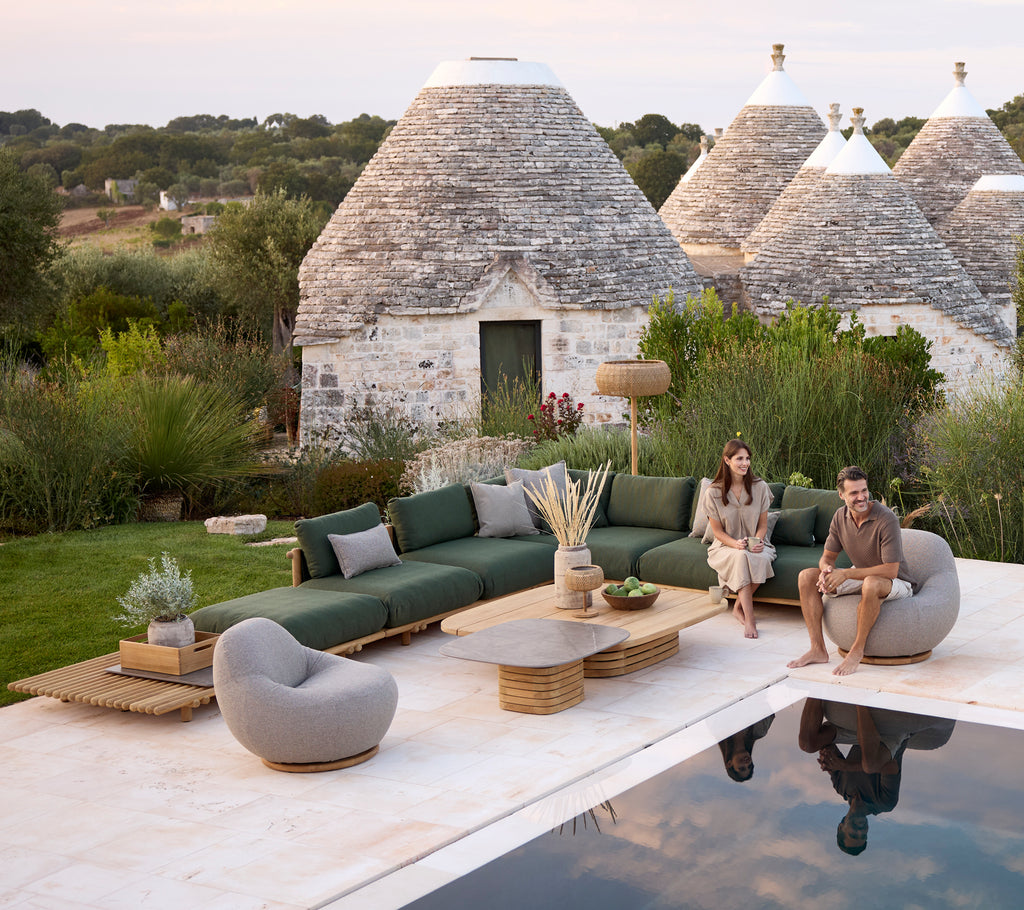 Moderner Außenbereich mit einer grünen Couch, einem grauen Stuhl und einem runden Couchtisch.