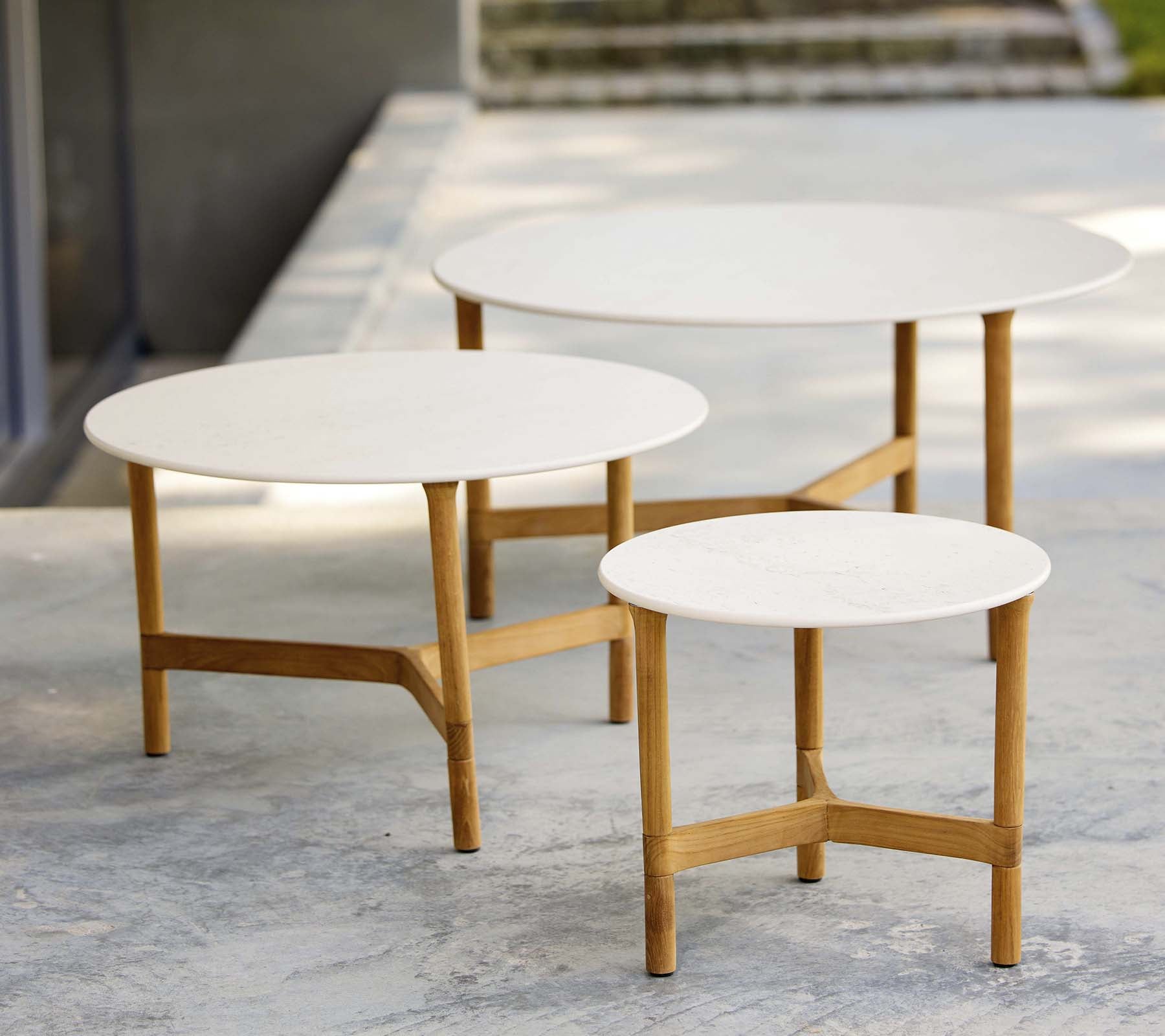 Drei moderne Couchtische in verschiedenen Größen mit weißen Oberflächen und Holzbeinen, die ein stilvolles und minimalistisches Design zeigen.