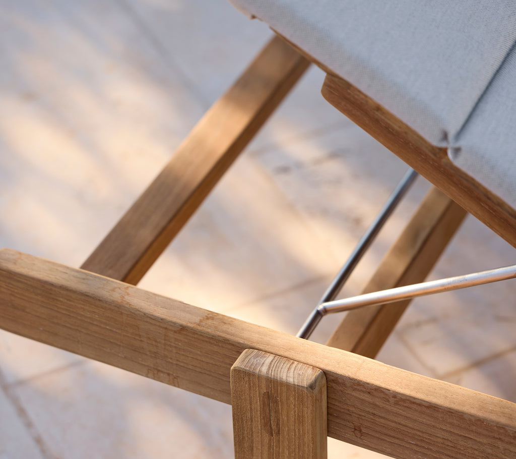 Modernes Loungestuhl mit einem grauen Kissen und Holzrahmen.