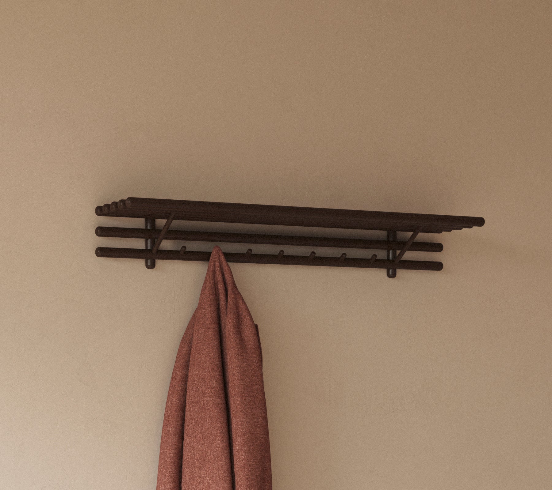 Ein minimalistisches Regal mit mehreren Haken, die ein hängendes Tuch halten, entworfen für praktische Aufbewahrung und Organisation.